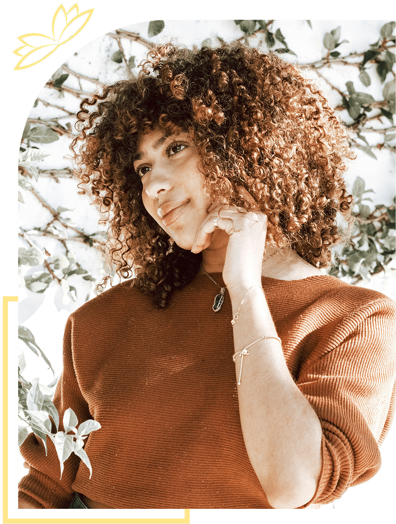 Woman with curly hair drinking from a leaf-design mug in bed.