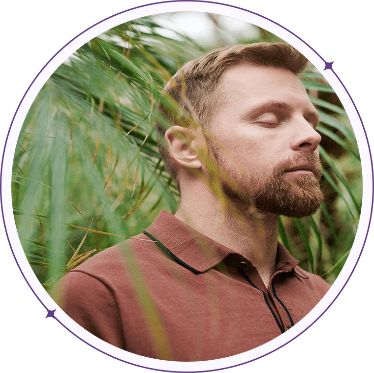 Laughing man in a grassy field, framed by a purple circle.