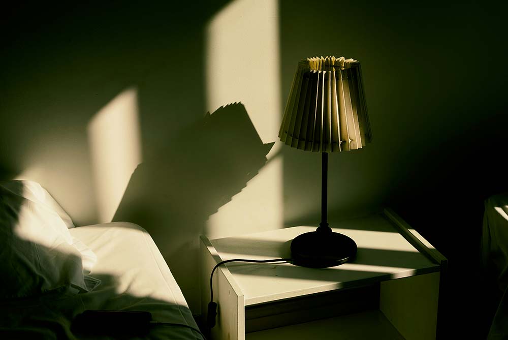 A Lamp Casts a Shadow on the Wall Next to a Bed
